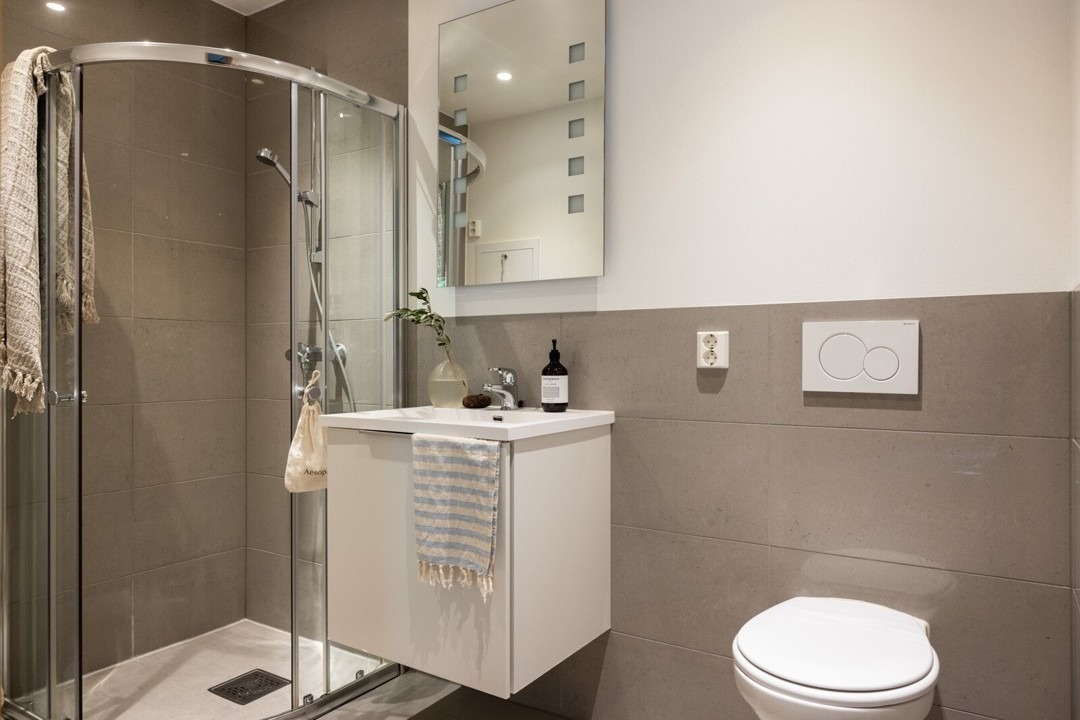 Stort og romslig bad med vaskemaskin som er installert til venstre for dusjen.